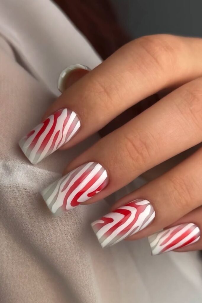 White coffin nails with bold red candy cane swirl pattern.